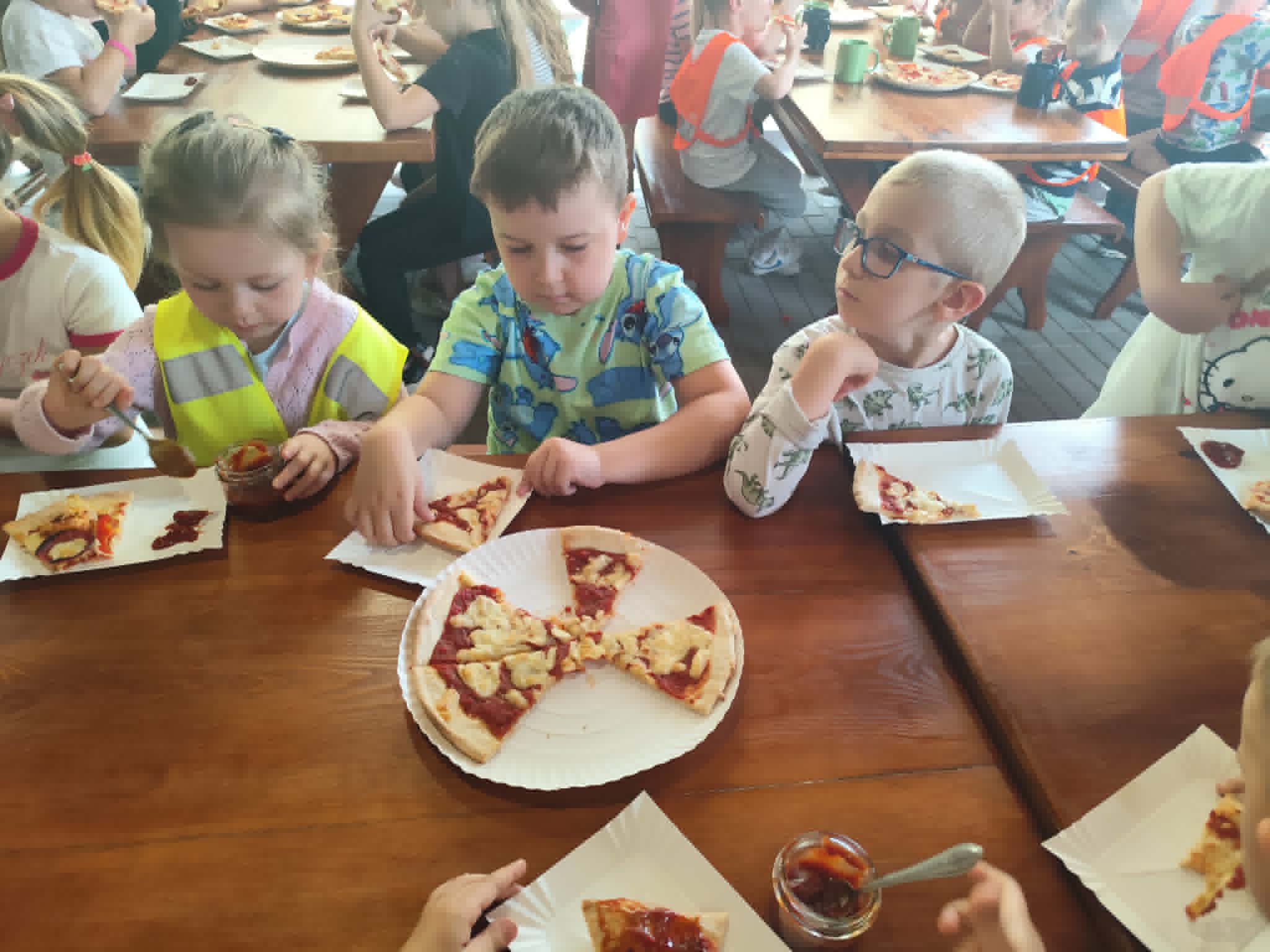 Dzieci przy stołach i pizza